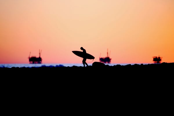 Offshore oil rigs and surfer