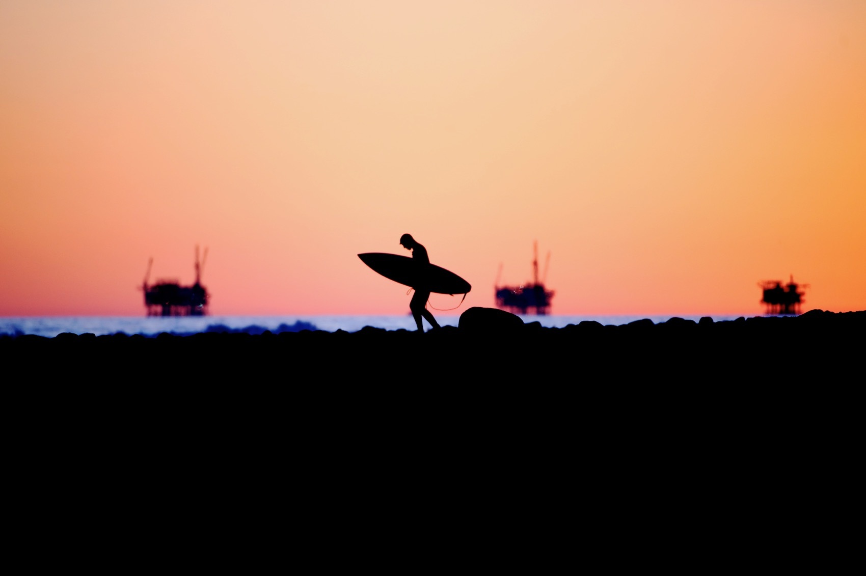 Offshore oil rigs and surfer